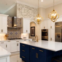 Modern kitchen extensions feature white cabinets, a blue island, gold pendant lights, stainless steel appliances, patterned tile backsplash, and marble accents. Three black chairs sit at the island in this bright and elegant space.